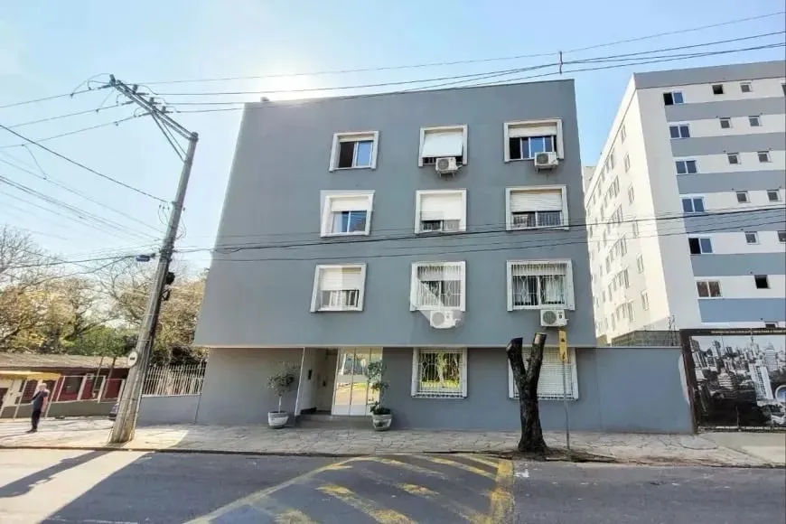 Facade of Edifício Veranópolis, a four-story gray building with white windows on a tree-lined street in downtown Novo Hamburgo